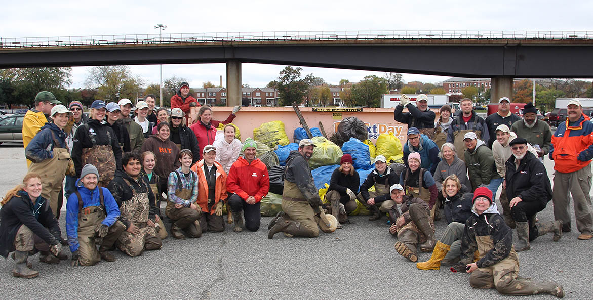 Large group of people in foul weather gear gather for a group photo.
