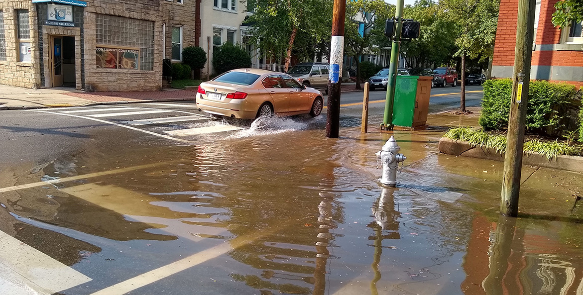 A car splashes through a flooded street.