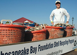 CBF staff member stands amid orange baskets filled with oyster shell.